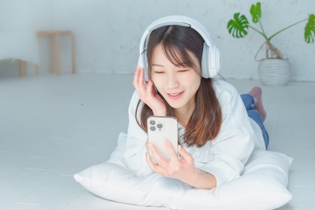 寝転んでスマホを見ている女性